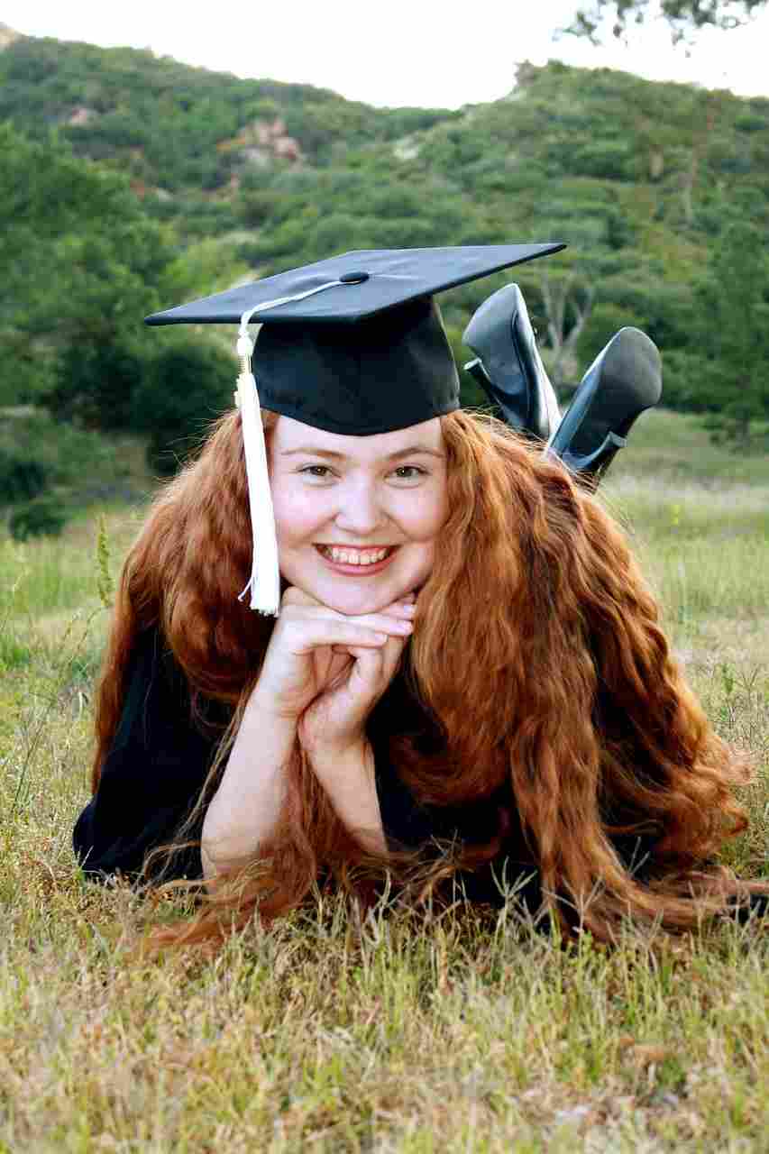 Smiling college graduate lying on the grass in a cap and gown, celebrating academic success while exploring Student Loan Hero resources, understanding Student Loan Forgiveness, managing Student Loan Payments, researching Student Loan Forgiveness Programs, and comparing Private Student Loan Refinance options.