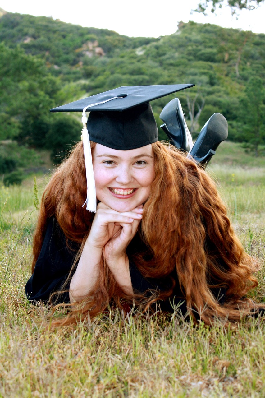 Smiling college graduate lying on the grass in a graduation cap and gown while planning for Student Loan Payments, researching Student Loan Forgiveness, comparing Student Loan Forgiveness Programs, exploring Private Student Loan Refinance options, and using resources like Student Loan Hero to manage educational debt after graduation.