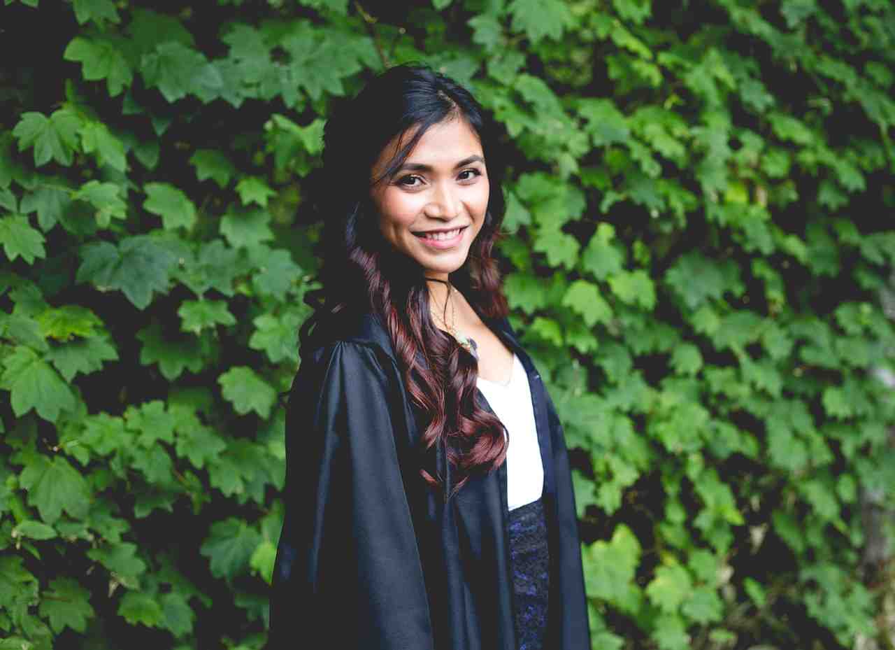 Graduate student wearing a cap and gown standing outdoors, representing the opportunities made possible through student loans that help finance higher education, career advancement, and professional development.