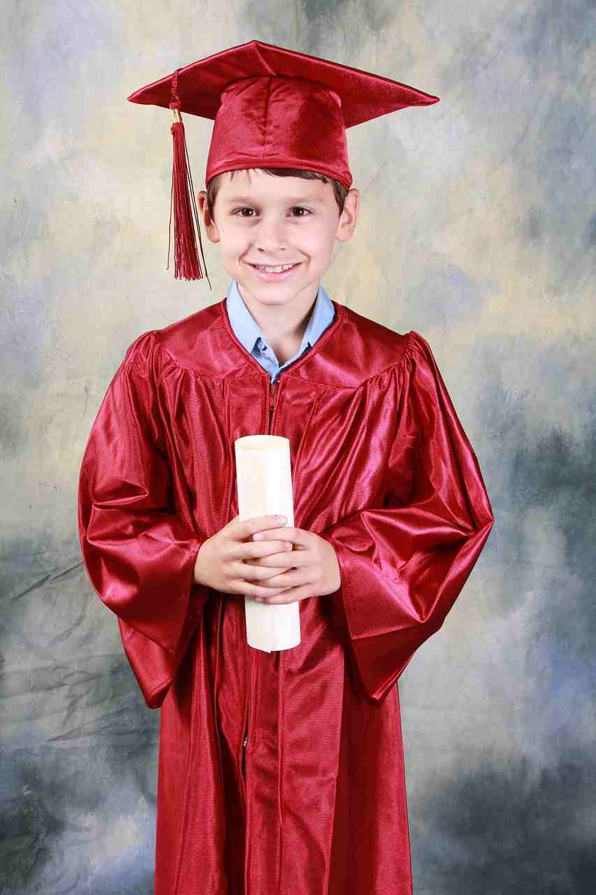 Young graduate in a red cap and gown holding a diploma, symbolizing educational achievement made possible through a Student Loan, responsible management of Student Loan Debt, access to Federal Student Aid, affordable College Loans, and Private Student Loans for College.
