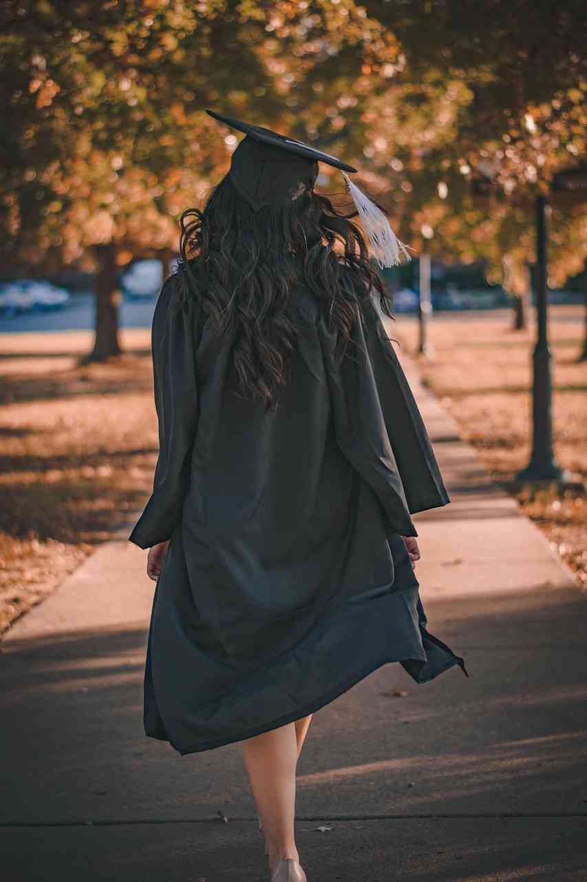 Graduate walking across a campus pathway in a cap and gown, representing financial freedom through Consolidate Student Loans, comparing options with a Refinance Student Loans Calculator, evaluating Refinance Student Loans Rates, understanding Student Loan Deferment, and learning How to Consolidate Student Loans after graduation.