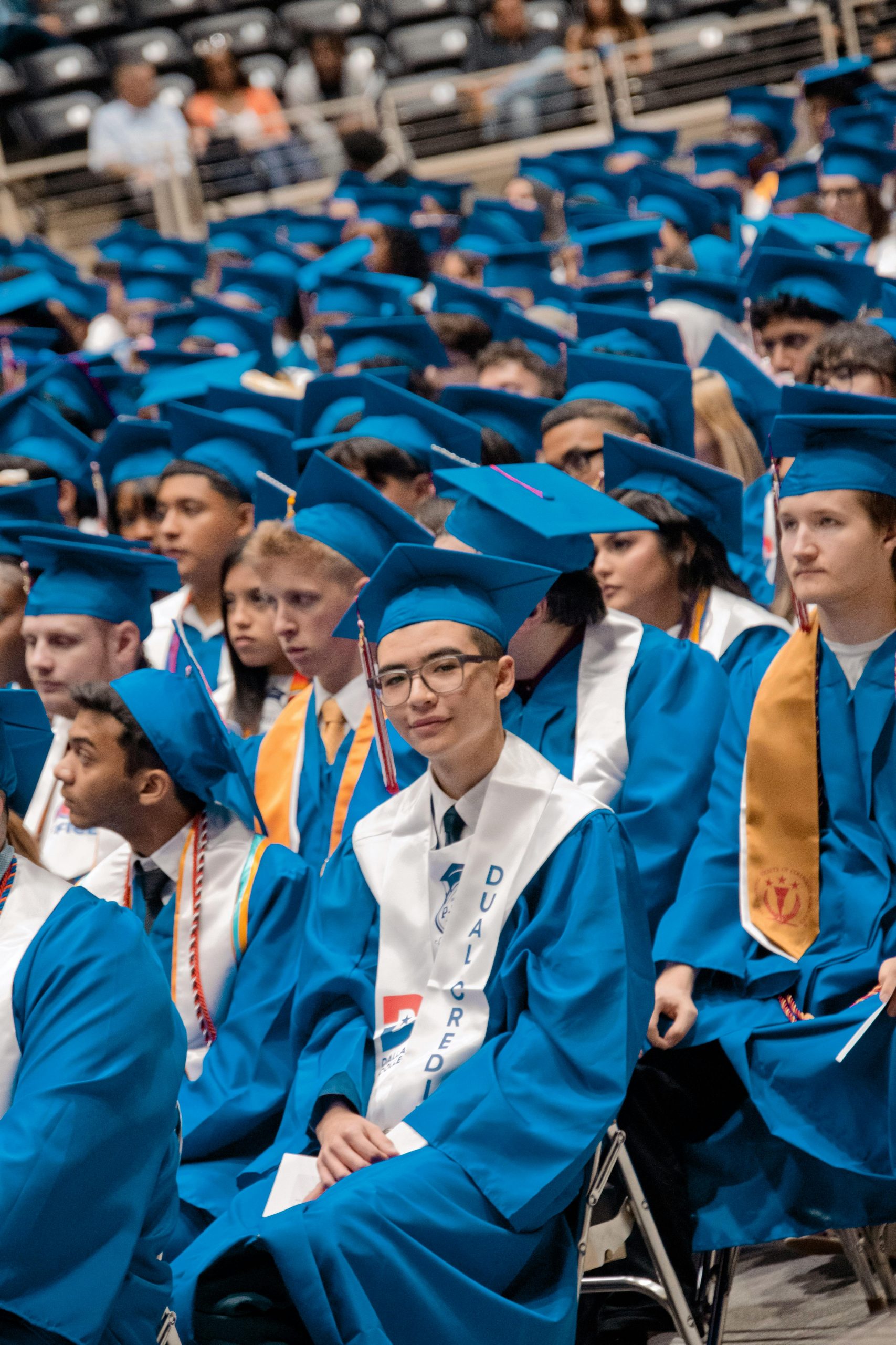 Students wearing blue graduation caps and gowns during a commencement ceremony, exploring Education Loans, learning How to Apply for Student Loans, completing a Student Loan Application, accessing their Student Loan Login, and returning to the Home page for educational financing resources.