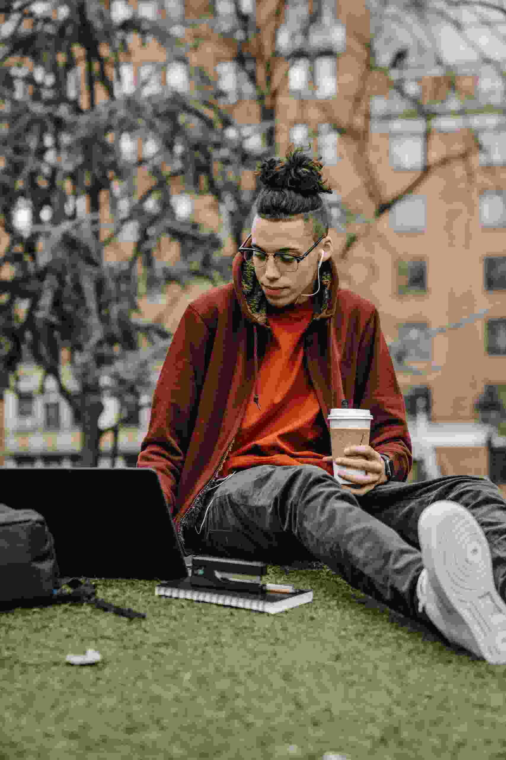 College student studying outdoors with a laptop and coffee while researching Student Loan Lenders, exploring options to Refinance Student Loans for Lower Payments, and learning how to Refinance Student Loans Without a Cosigner to improve financial flexibility after graduation.
