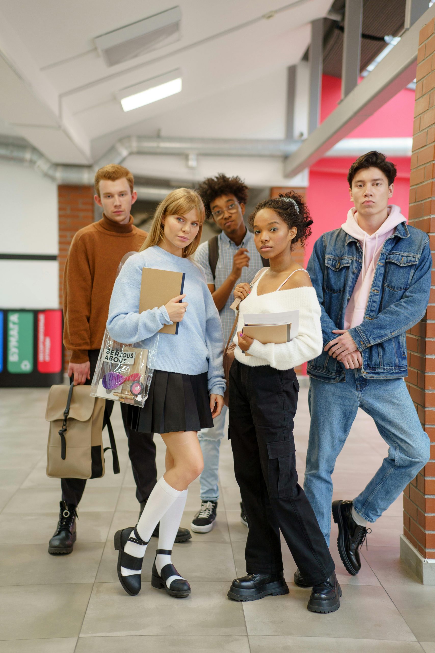 Group of diverse college students standing together in a campus hallway holding books and study materials while exploring Government Student Loans, researching Federal Student Loan Forgiveness opportunities, comparing Student Loan Interest, evaluating options to Refinance Student Loans, and reviewing offers from various Student Loan Companies to help finance higher education.