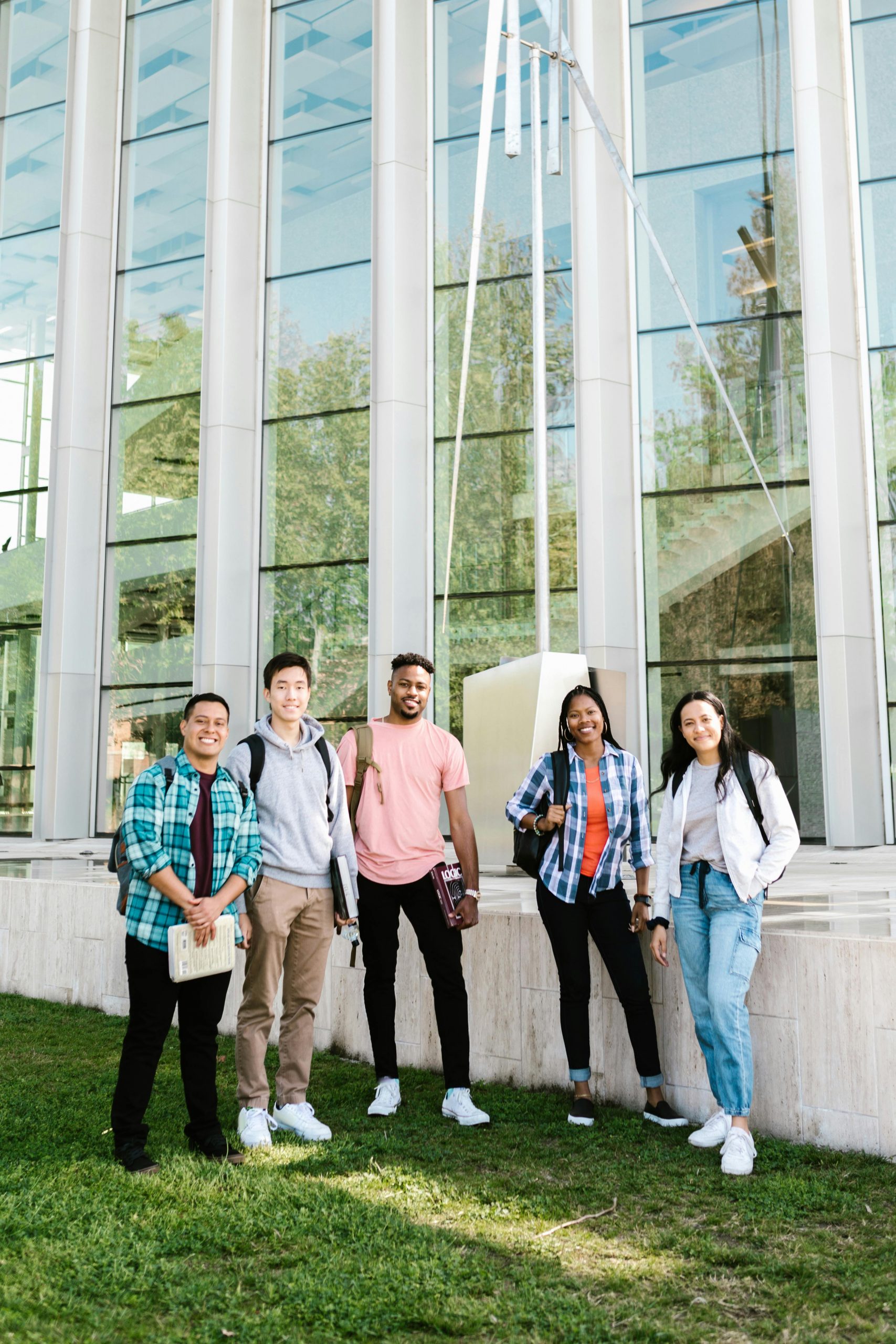 Diverse college students standing outside a university building while researching how to Compare Student Loan Refinance Rates, asking Can You Refinance Student Loans, learning How to Refinance Student Loans, understanding How to Refinance a Student Loan, and evaluating competitive Refinance Student Loan Rates for lower monthly payments.