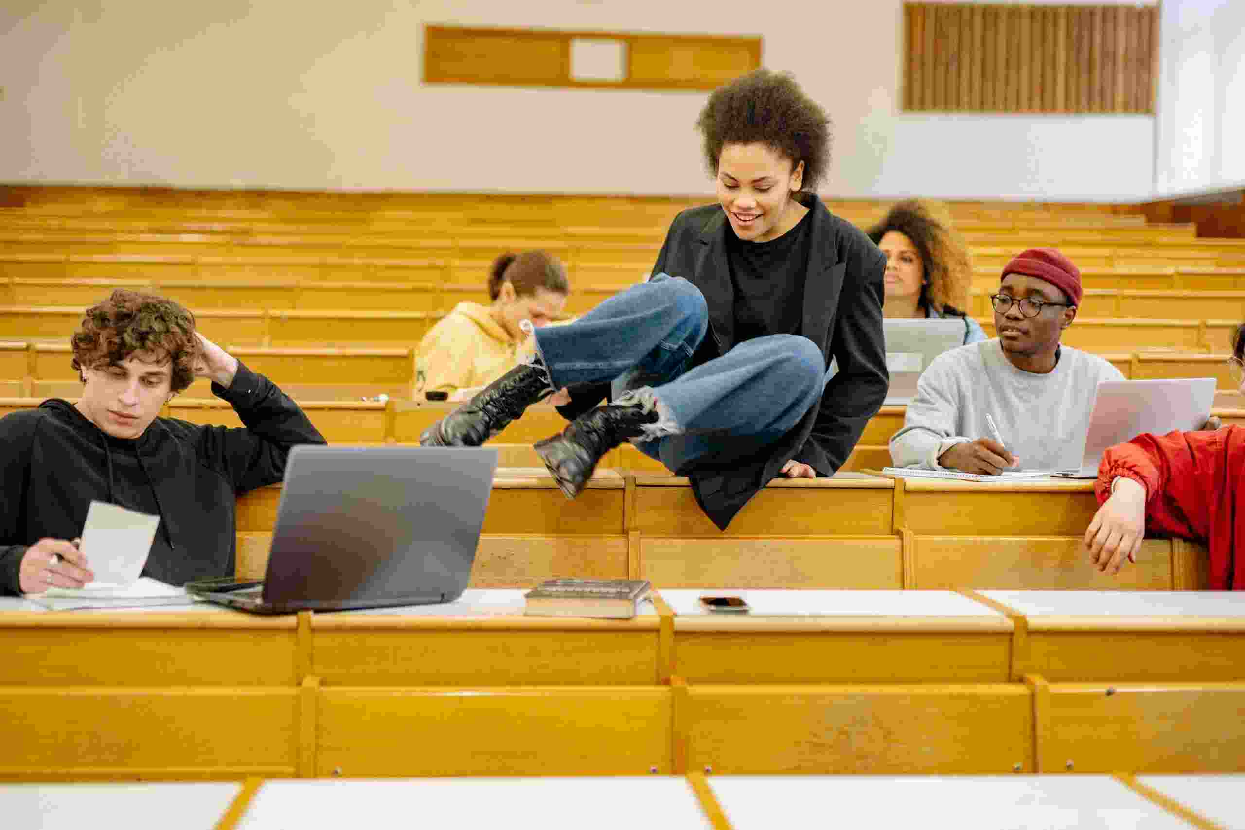 College students studying in a lecture hall while exploring Student Loan Consolidation Refinance options, evaluating a Grad Plus Loan, comparing Low Interest Student Loan Refinance programs, checking Student Loan Refinance Rates Today, and researching how to Refinance Student Loans after graduation.