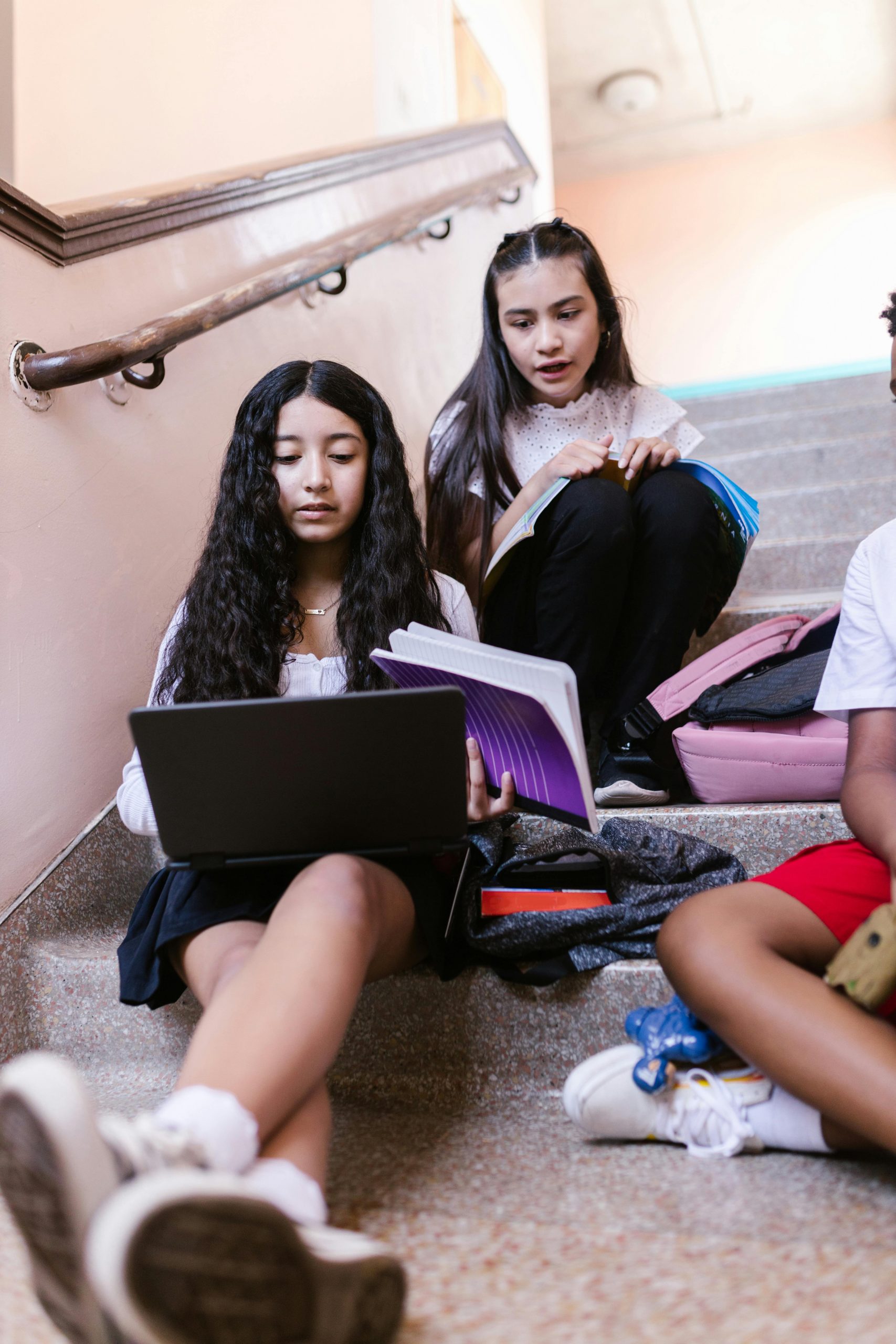 Students studying together on school stairs using a laptop, notebooks, and textbooks while researching Refinance Private Student Loans, comparing Student Loan Interest Rates, using a Student Loan Payment Calculator, reviewing Department of Education Student Loans, and learning How to Pay Off Student Loans efficiently after graduation.